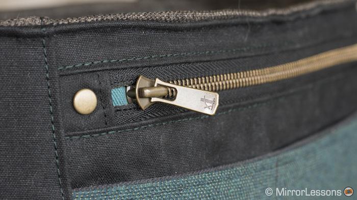 The main pocket closes with a brass zip